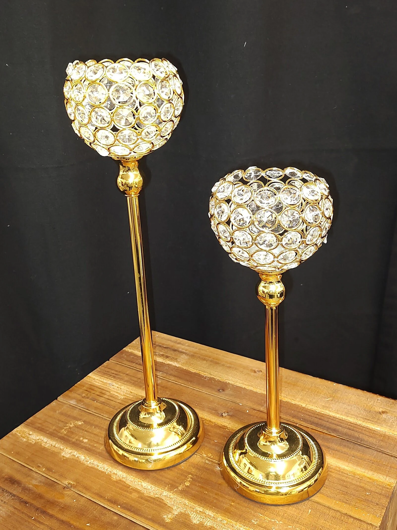 Two elegant gold and crystal candle holders on a wooden surface.