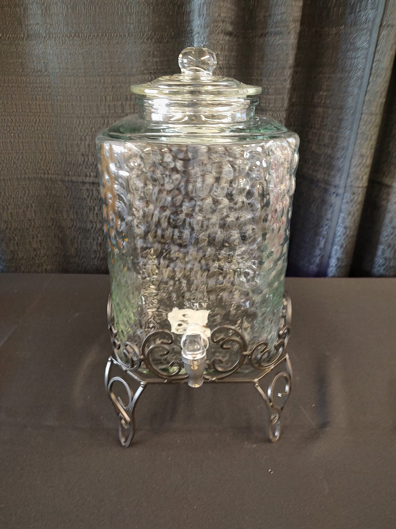Elegant glass beverage dispenser with a metal stand and spigot.