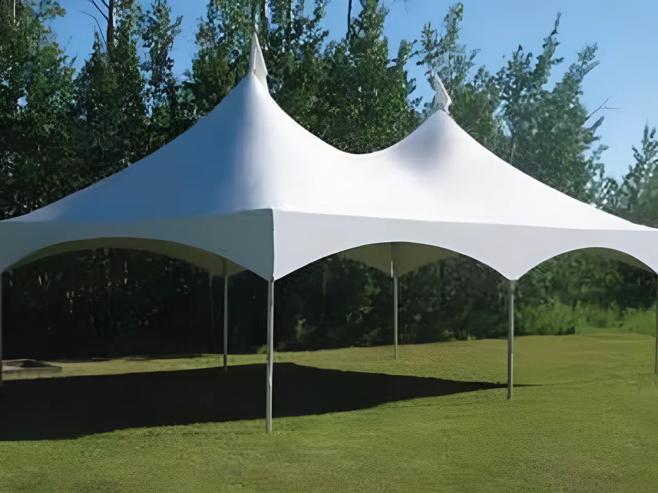 White double-peak canopy tent set up outdoors on grass.