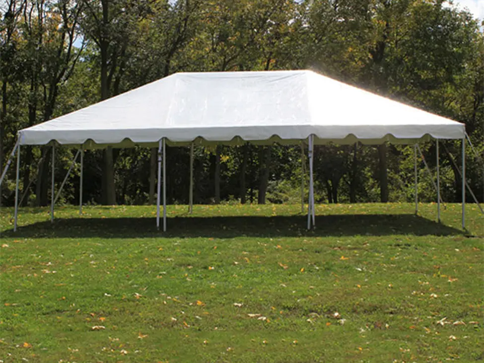 A large white event tent set up on a grassy field with trees in the background.
