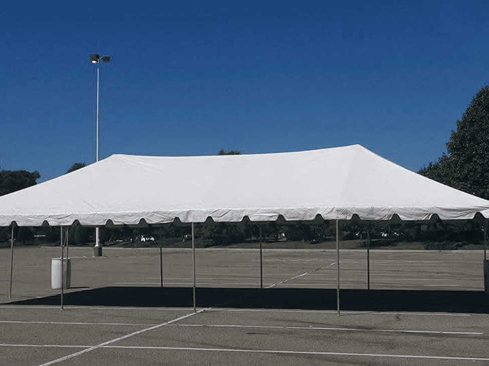 Large white event tent set up in an empty parking lot under clear blue sky.