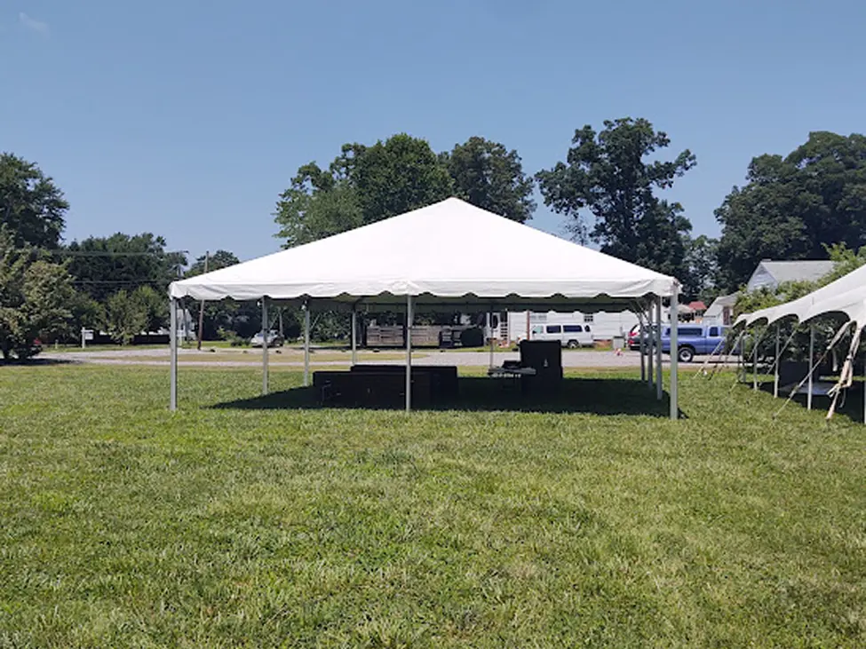 Large white event tent set up on green grass under clear blue sky.