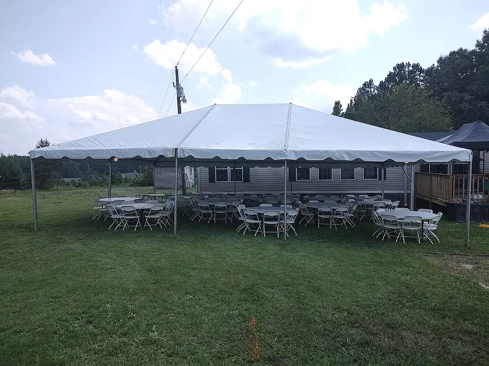 Large white event tent with tables and chairs set up on grass.