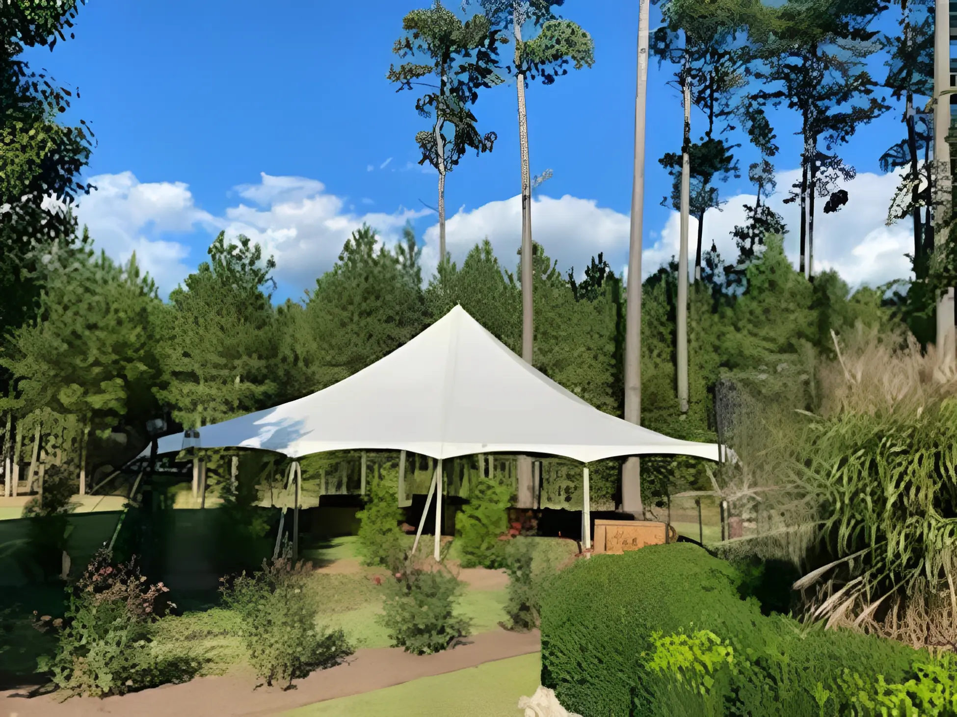 White tent canopy in a landscaped garden under blue sky.