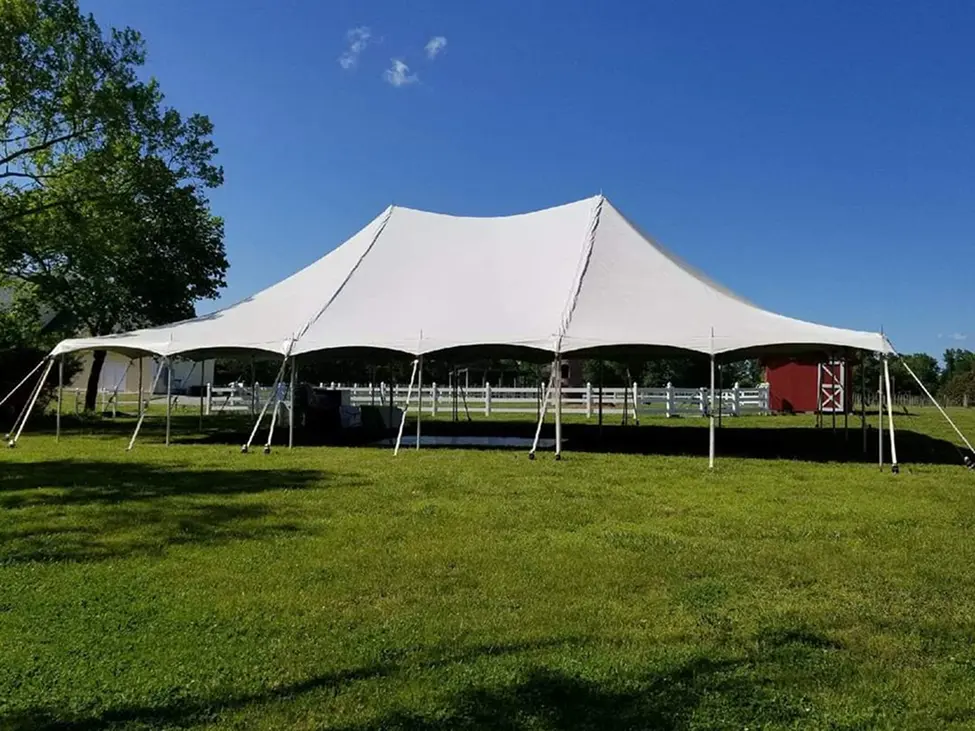 Large white tent set up on green grass under a clear blue sky.