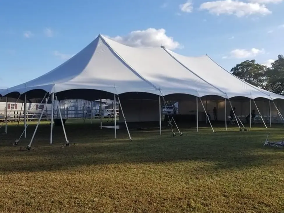 Large white event tent set up on grassy field under clear sky.