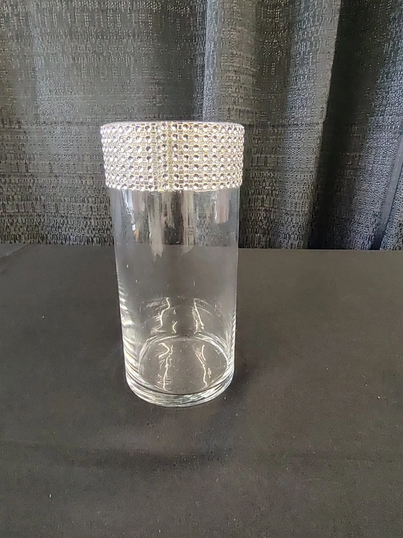 A clear glass vase with a crocheted or knitted white cover on top.