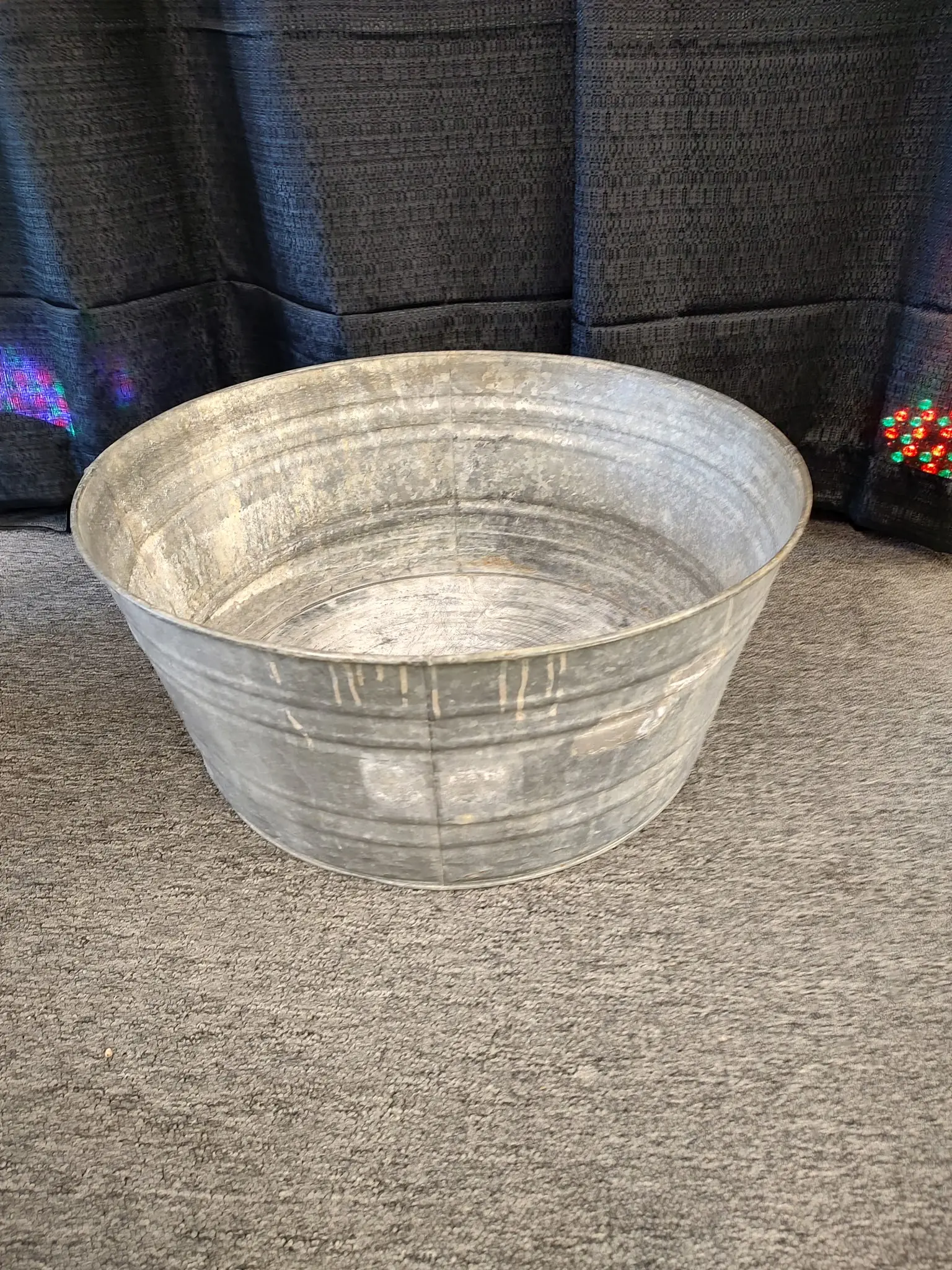 A galvanized metal tub on a carpeted floor.