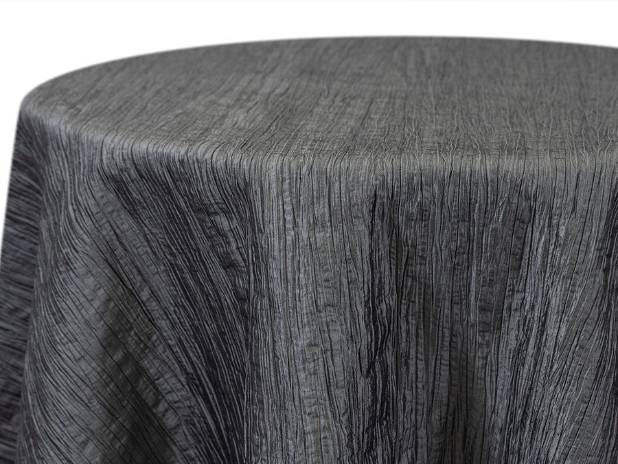Close-up of a grey textured fabric tablecloth draped over a round table.