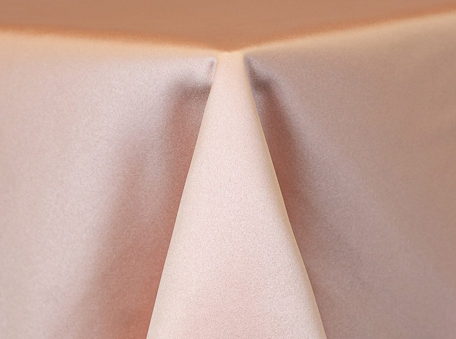 Close-up of a beige tablecloth draped over a table corner.