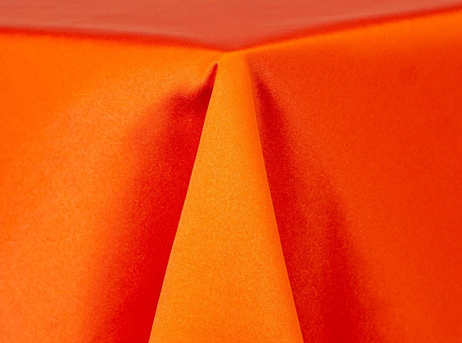 Close-up of bright orange fabric with folds and texture.