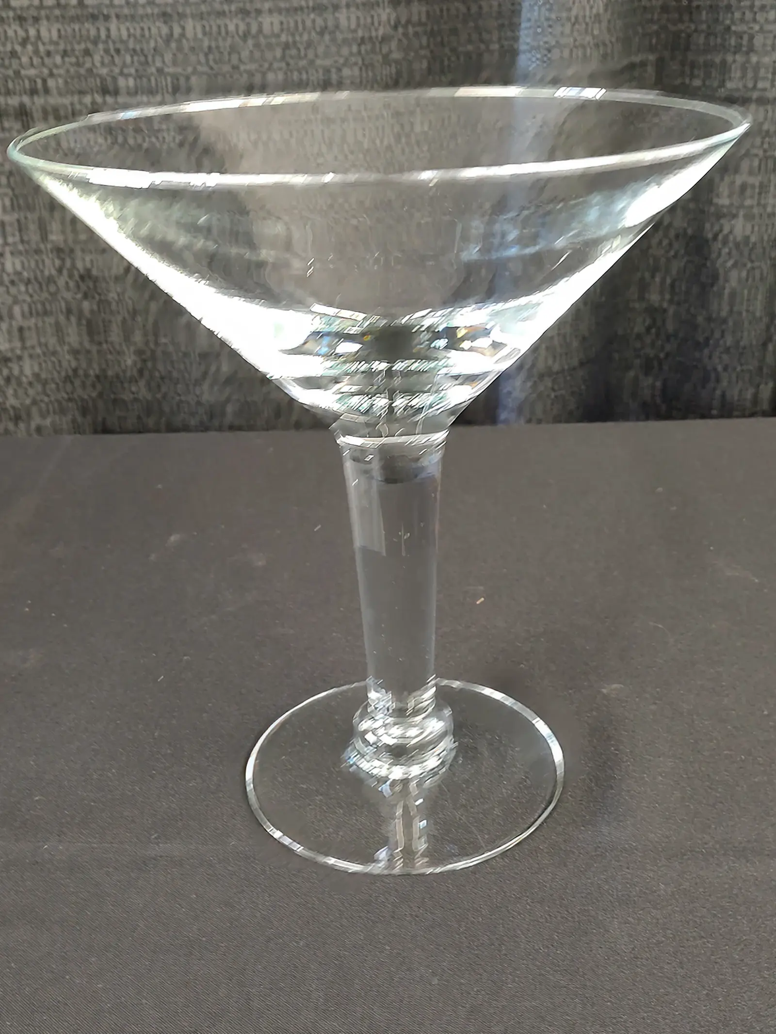 A clear martini glass on a gray surface.
