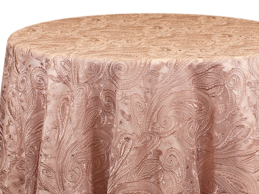 Round table covered with a textured pink tablecloth.