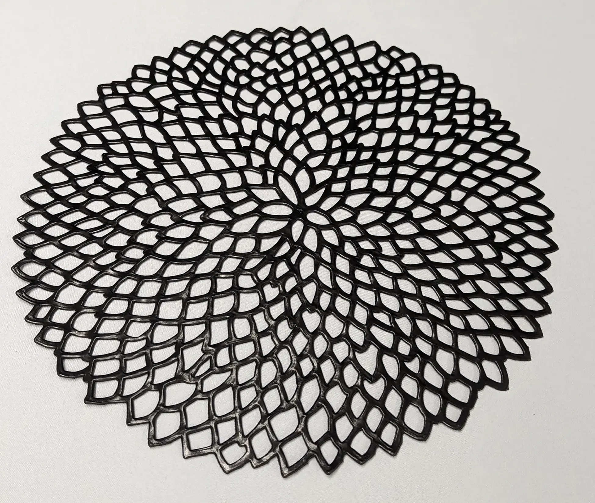 Black intricately woven circular mat with geometric pattern.