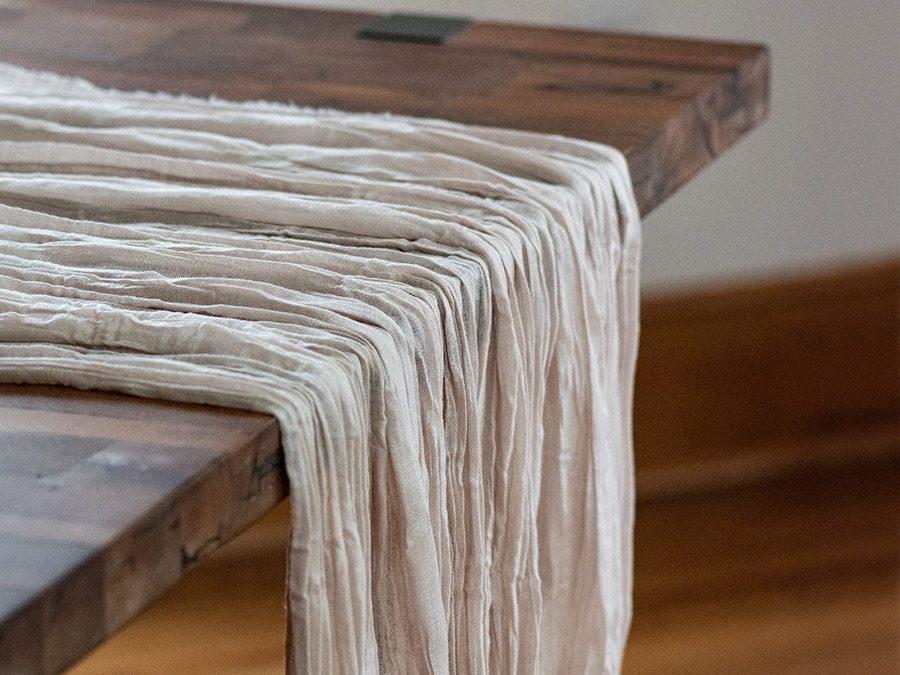 Soft beige fabric draped over a wooden bench edge.