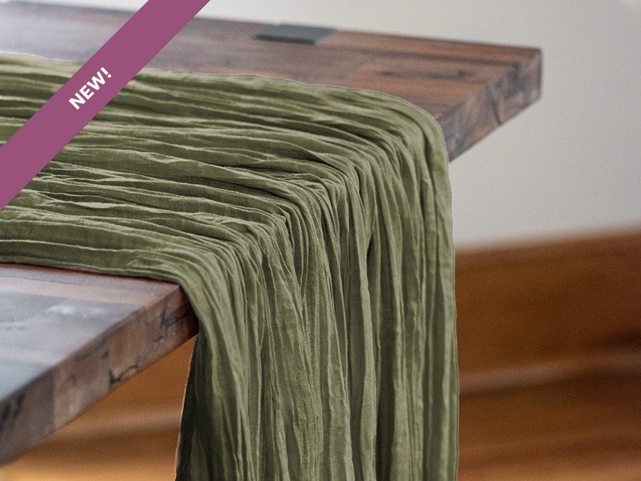 Soft olive green velvet fabric draped over a wooden table.