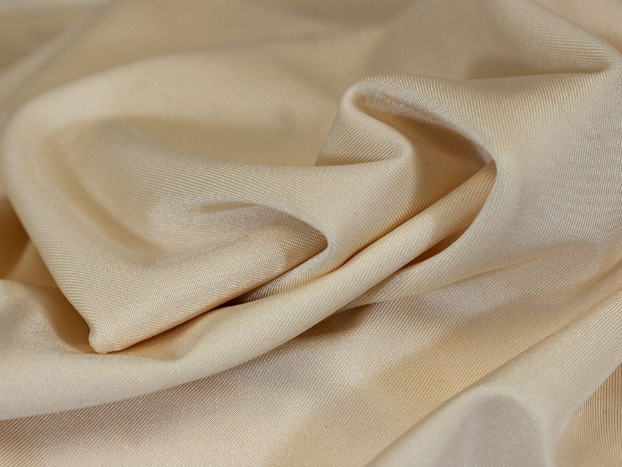 Soft beige fabric with gentle folds and a smooth texture.