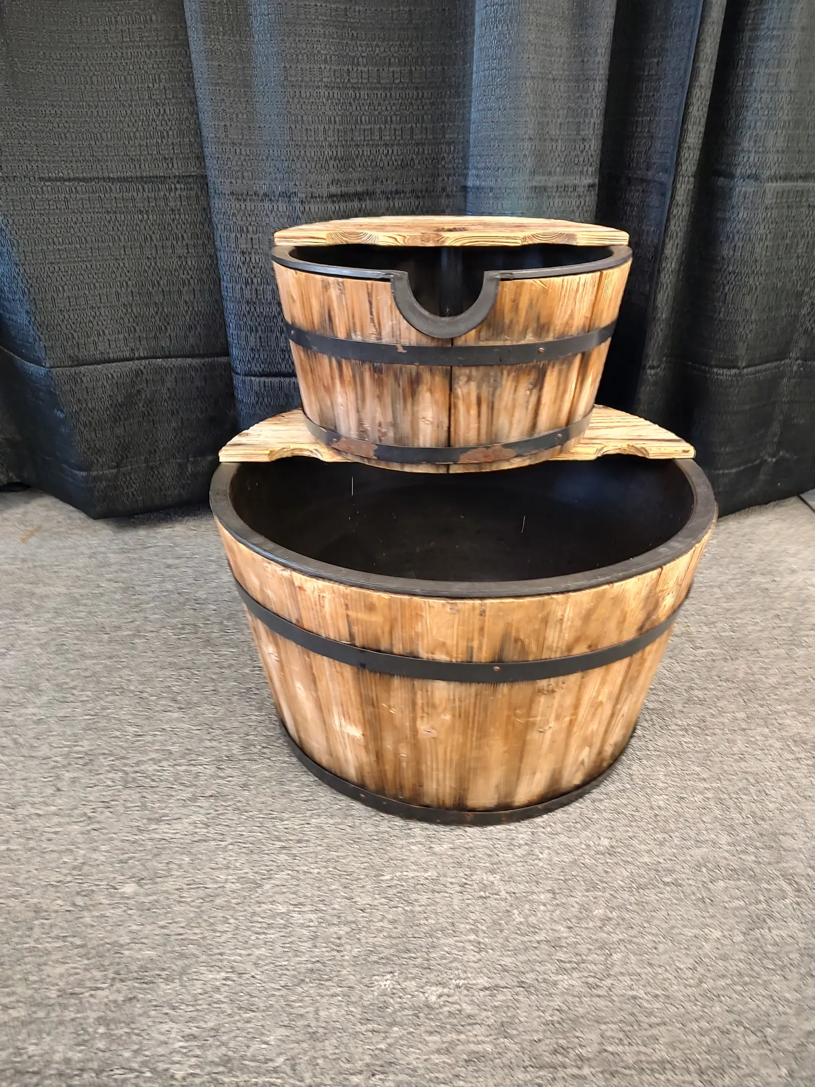 Two-tier wooden barrel planters with black liners.
