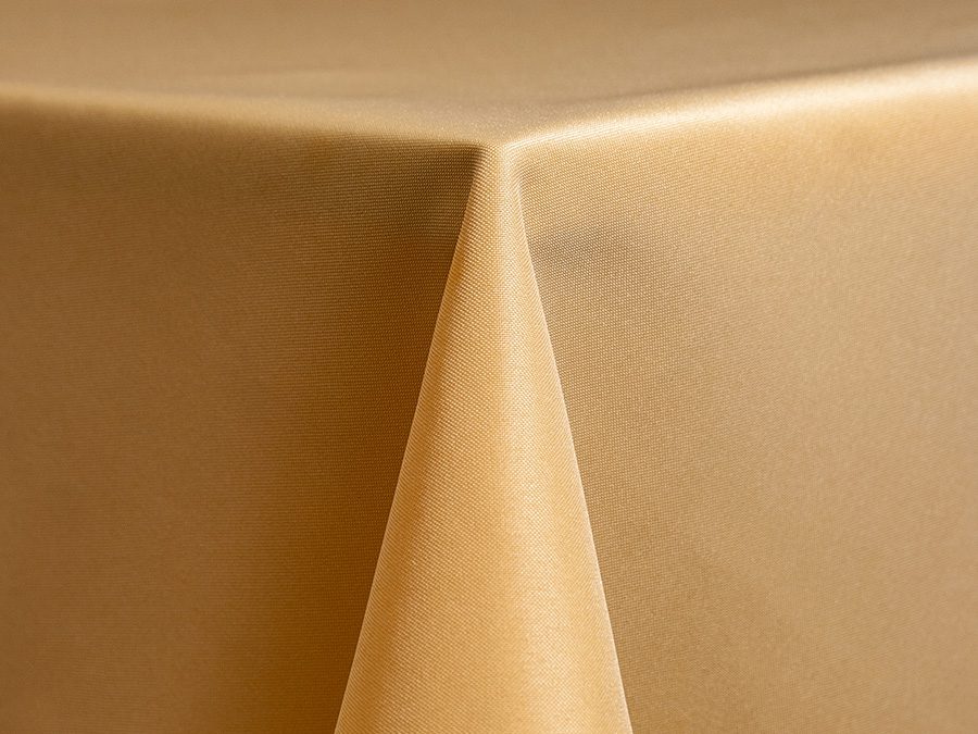 Close-up of a beige tablecloth corner hanging over a table edge.