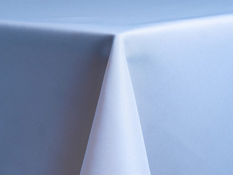 Close-up of a crisp white tablecloth corner on a table.