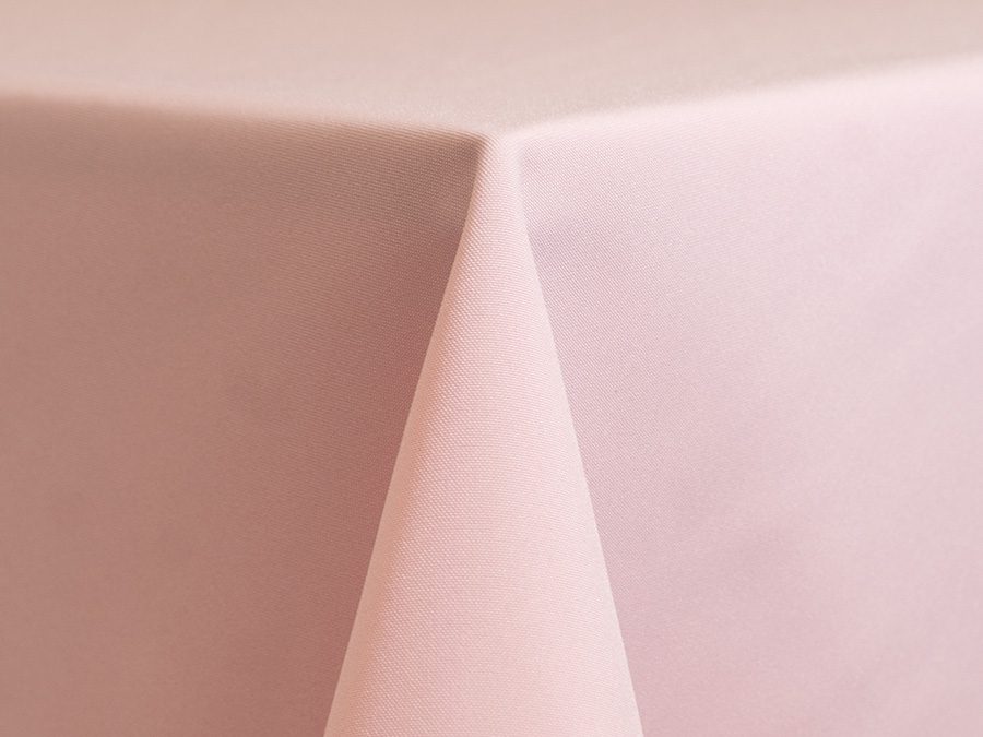 Close-up of a corner of a light pink tablecloth on a table.