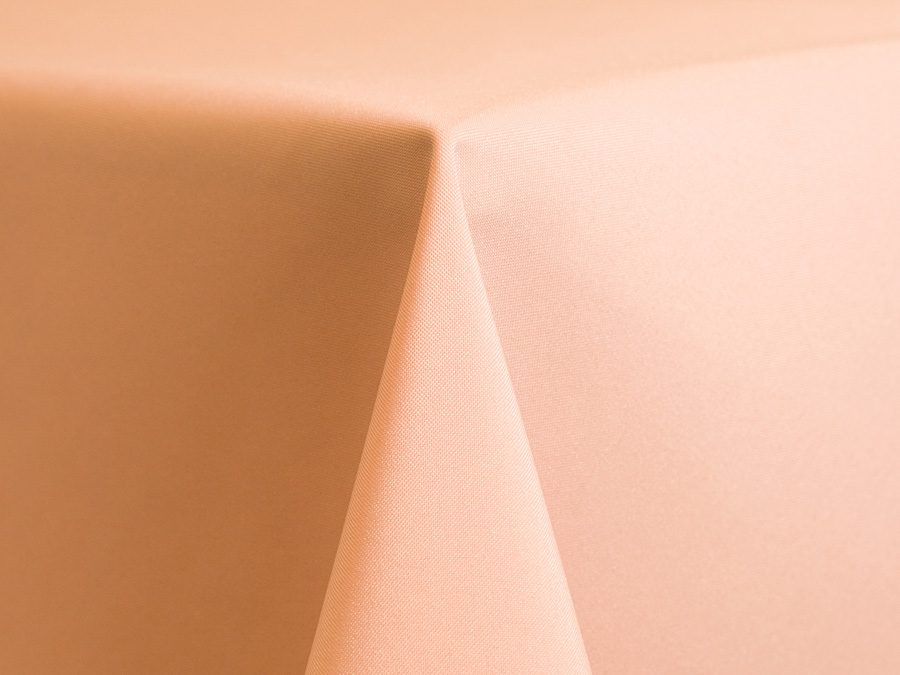 Close-up of a pastel peach tablecloth corner with soft folds.