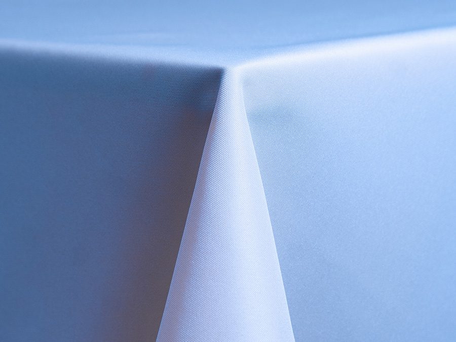 Close-up of a neatly folded white tablecloth corner on a table.