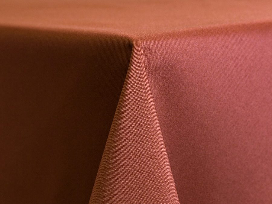 Corner of a table with two overlapping tablecloths in brown and pink.