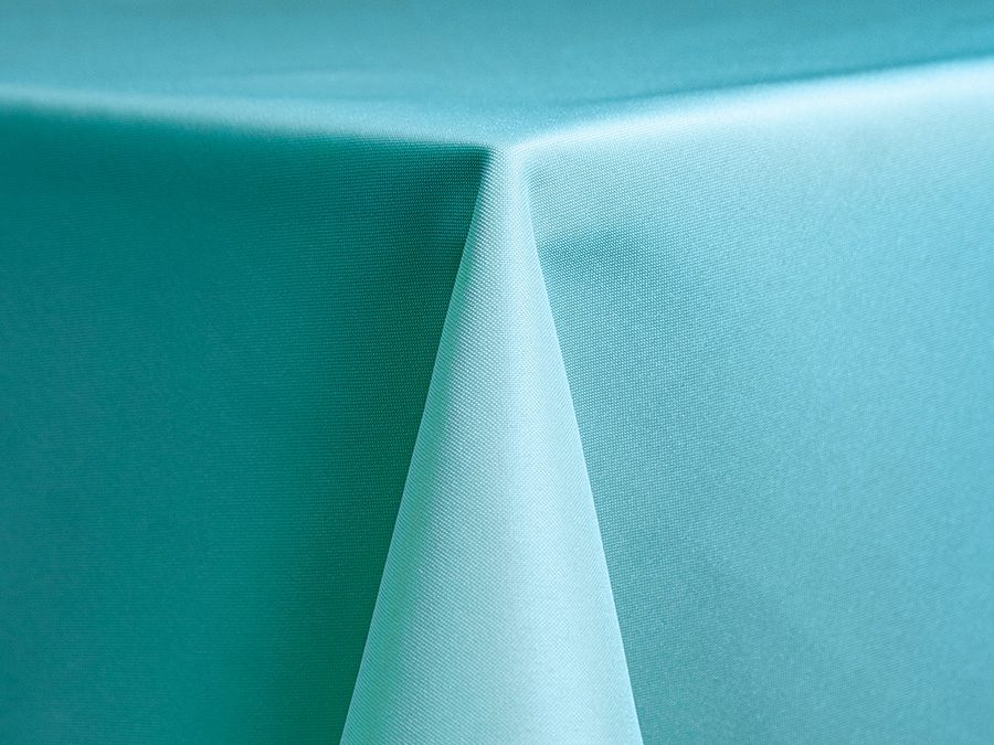 Close-up of a light blue tablecloth corner draped over a table.