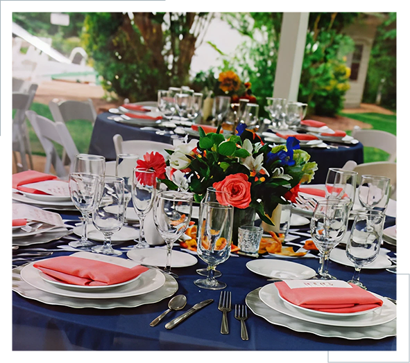Elegant outdoor table setting with navy tablecloths and floral centerpieces.