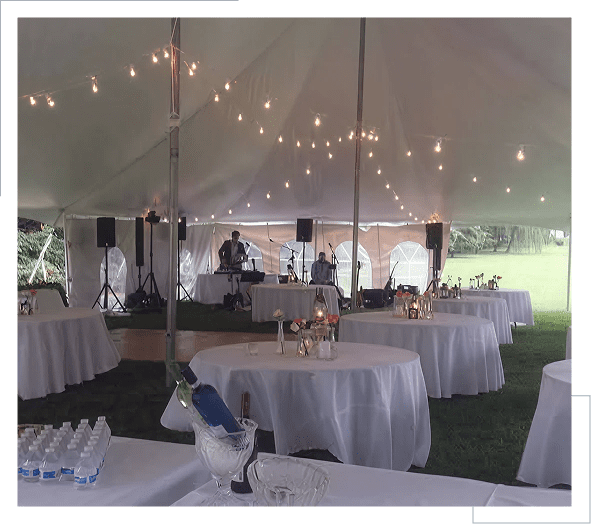 A spacious event tent with round tables and string lights.